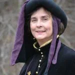 Headshot of Ingrid Towey wearing a chaperone hat and houppelande